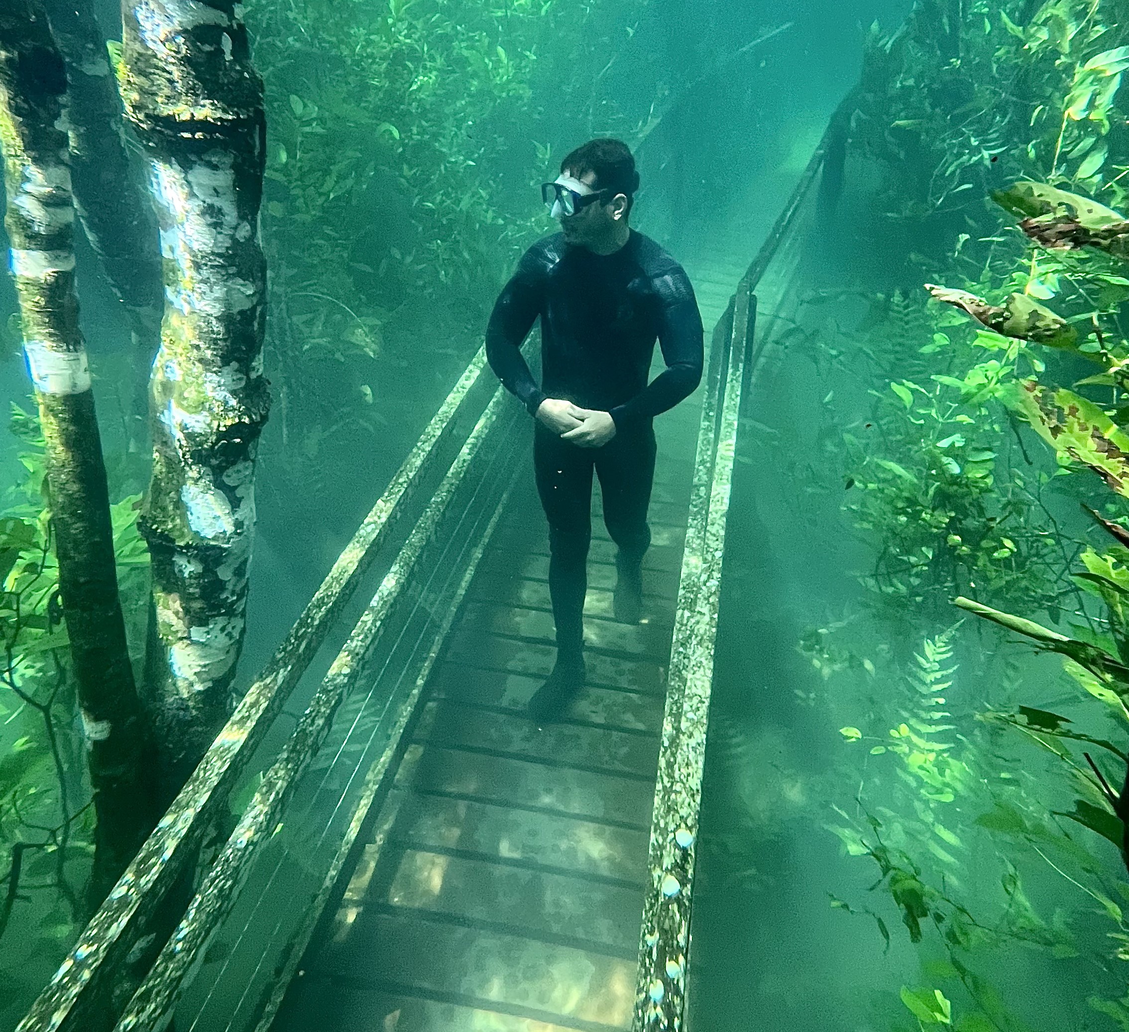 Turista caminha na trilha submersa e com águas cristalinas no Recanto Ecológico Rio da Prata